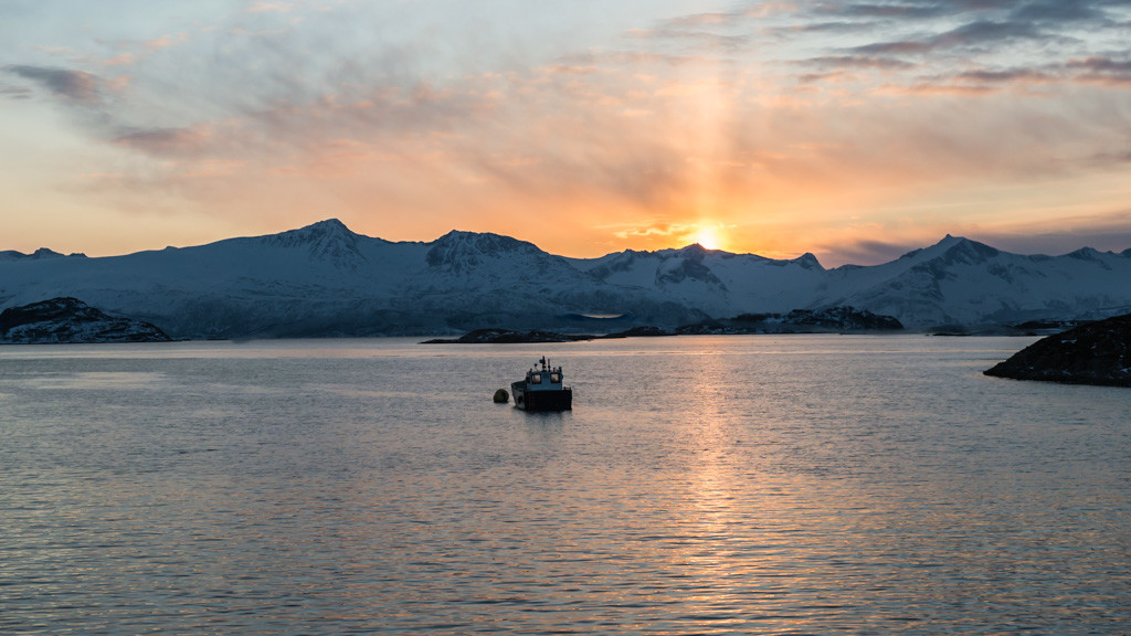 Boot im Sonnenuntergang vor den  Schneebedeckten Gipfeln in Troms